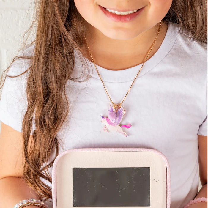 Child holding a pink jewelry box with jewelry inside, wearing a white shirt and colorful skirt.